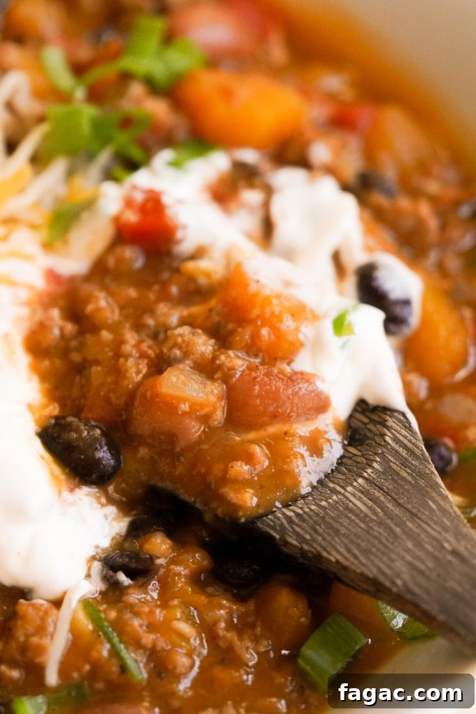 Hearty Butternut Squash and Turkey Chili Recipe 8 close up shot of butternut squash chili with a spoon taking a spoonful