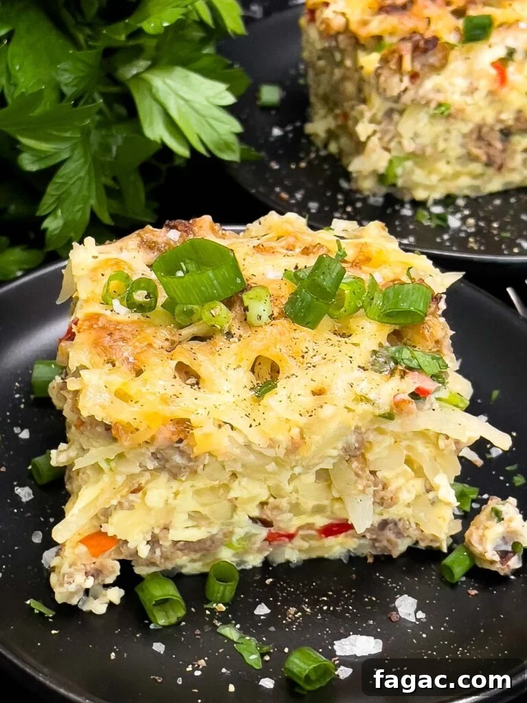 Sausage and Hashbrown Breakfast Casserole for 12 Guests 16 A serving of Sausage Hashbrown Breakfast Casserole on a dark plate, garnished with chopped green onions.