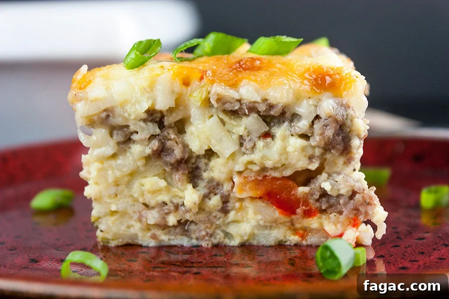 Sausage and Hashbrown Breakfast Casserole for 12 Guests 21 A slice of sausage hashbrown breakfast casserole on a red plate garnished with green onions.
