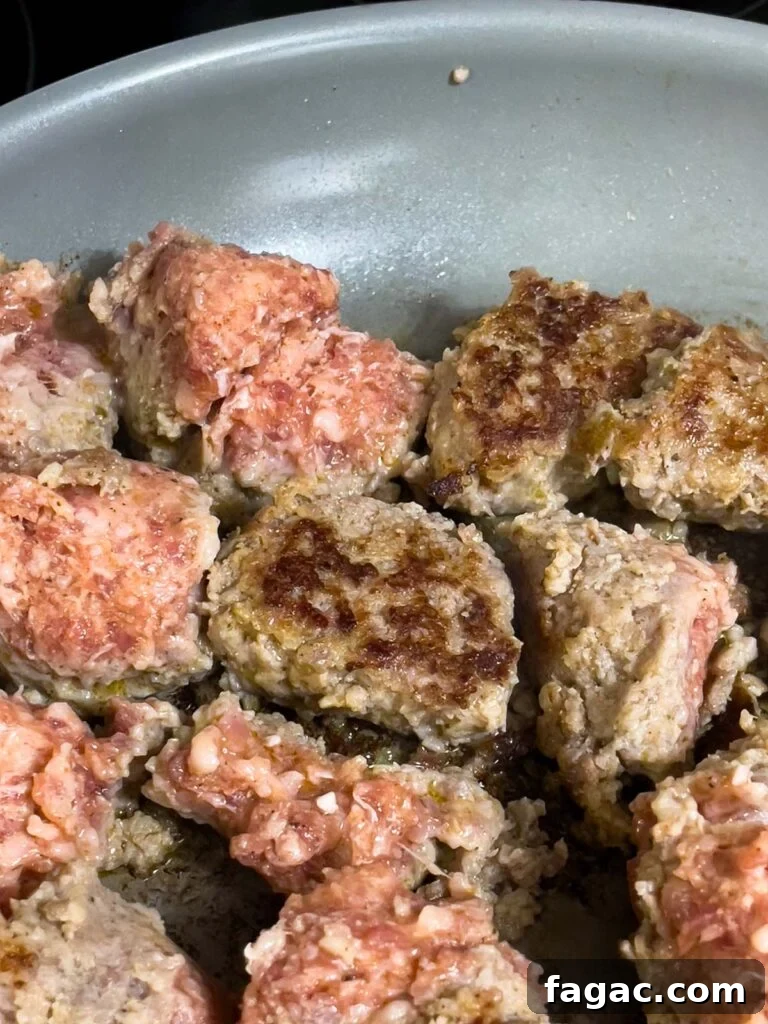 Sausage and Hashbrown Breakfast Casserole for 12 Guests 5 Partially cooked sausage pieces turned to show golden brown searing in a skillet.