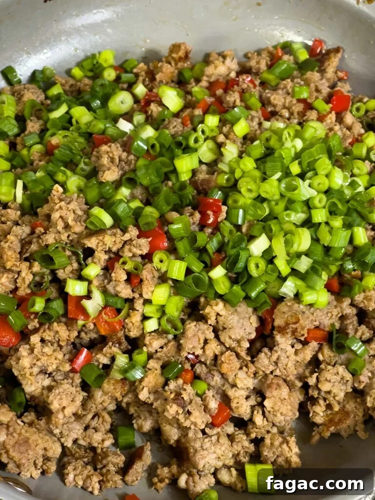 Sausage and Hashbrown Breakfast Casserole for 12 Guests 8 Chopped green onions added to cooked sausage and peppers in skillet.