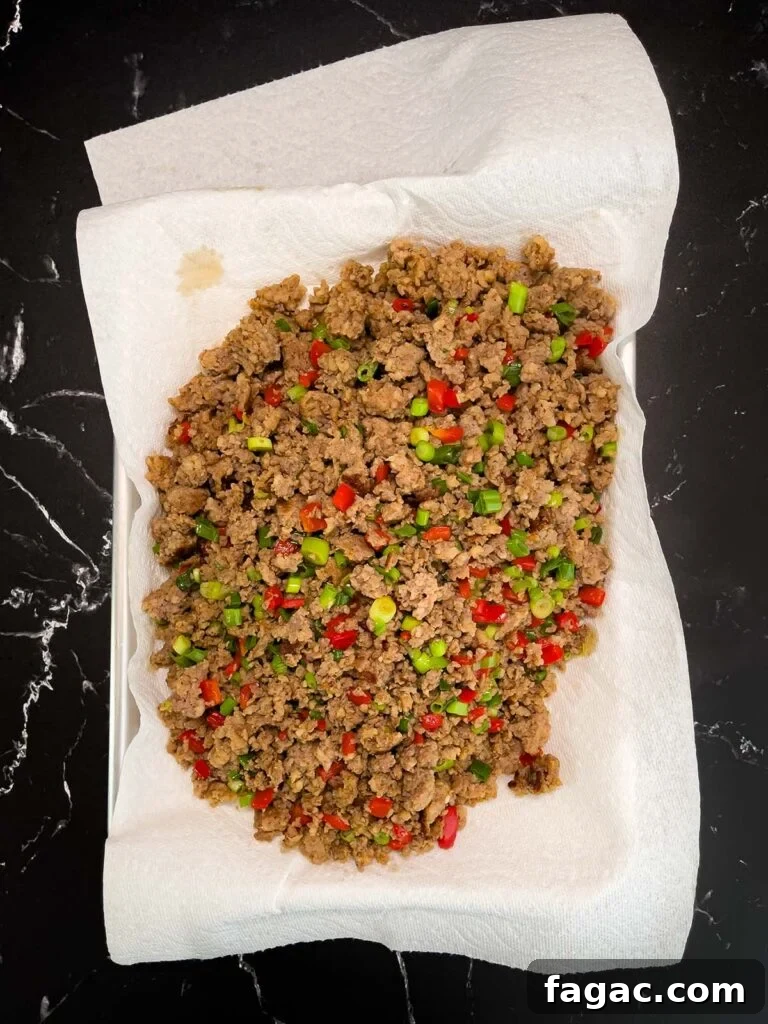 Sausage and Hashbrown Breakfast Casserole for 12 Guests 9 Cooked sausage mixture draining on a paper towel-lined plate.