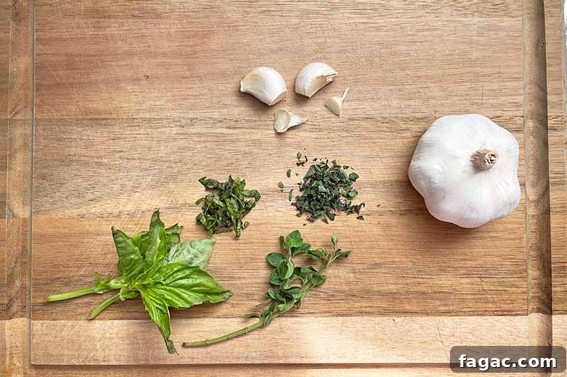 Oven-Roasted Tomato Sauce Recipe for Rich Homemade Flavor 7 Horizontal image of prepped herbs and garlic on a wooden cutting board.