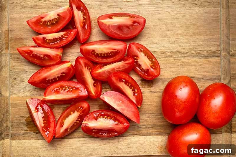 Oven-Roasted Tomato Sauce Recipe for Rich Homemade Flavor 8 Horizontal image of prepped fresh tomatoes on a wooden cutting board.