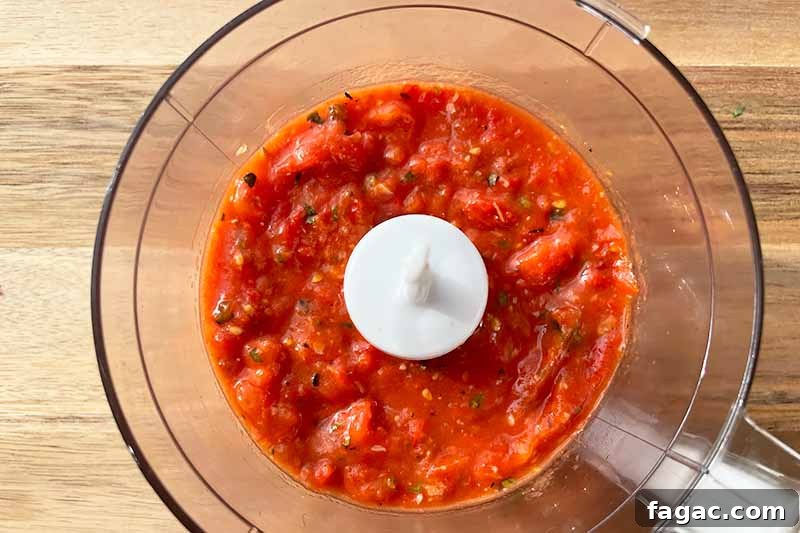 Oven-Roasted Tomato Sauce Recipe for Rich Homemade Flavor 10 Horizontal image of a pureed red liquid in a food processor.