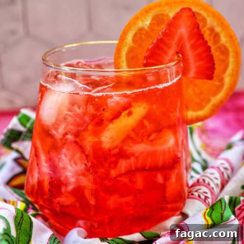 strawberry spritz with orange and strawberry garnish.