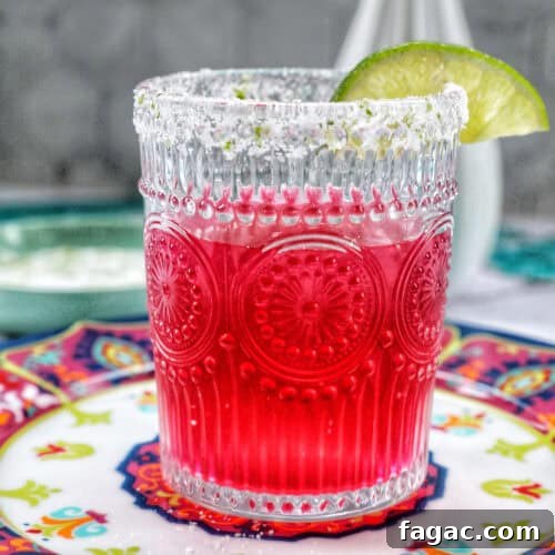 glass of prickly pear margarita with lime slice garnish.