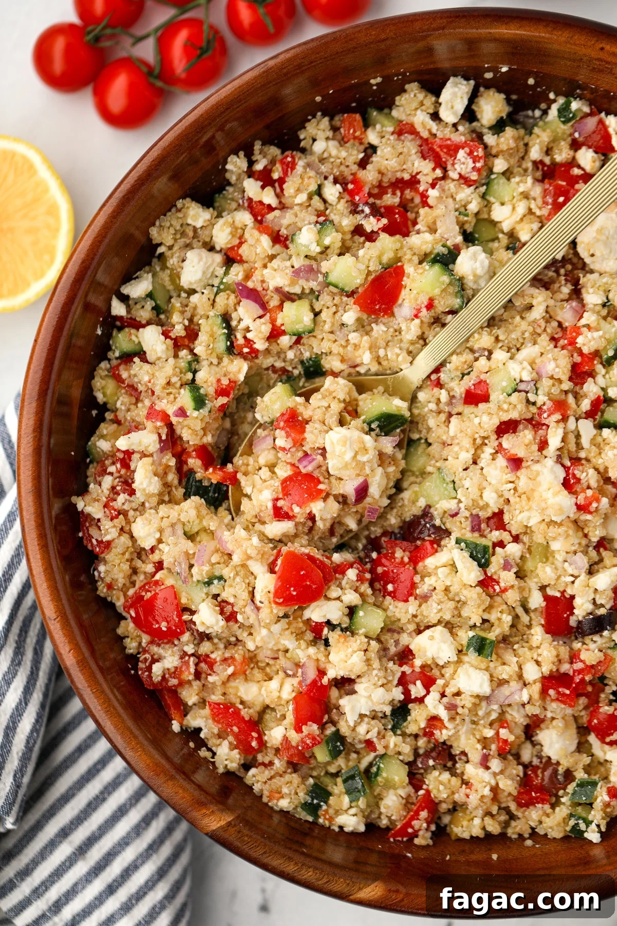 A large salad bowl filled with quinoa salad; pieces of red pepper, feta, and cucumber are visable.