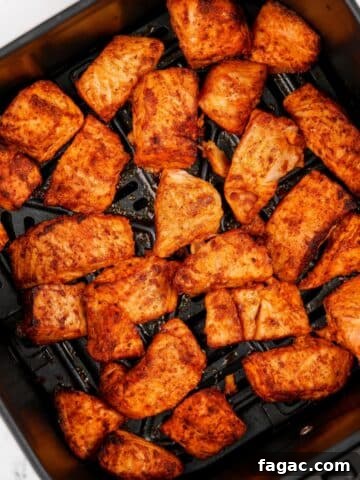 An air fryer basket filled with salmon bites.