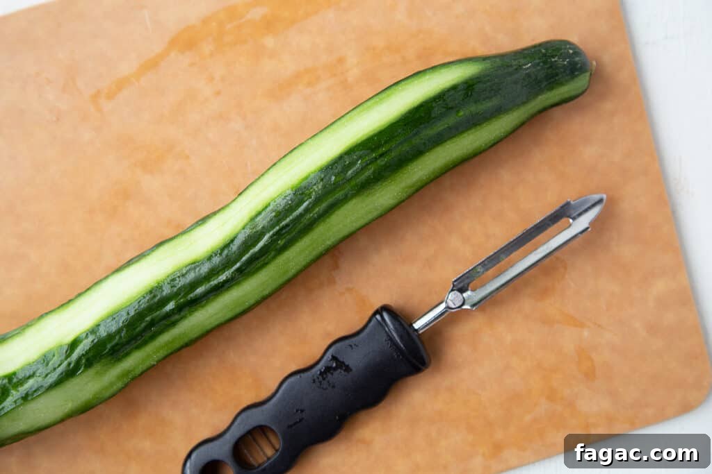 Mini Cucumber Sandwiches: Light Tea Sandwich Recipe 6 partially peeled cucumber on a wooden board next to a vegetable peeler.