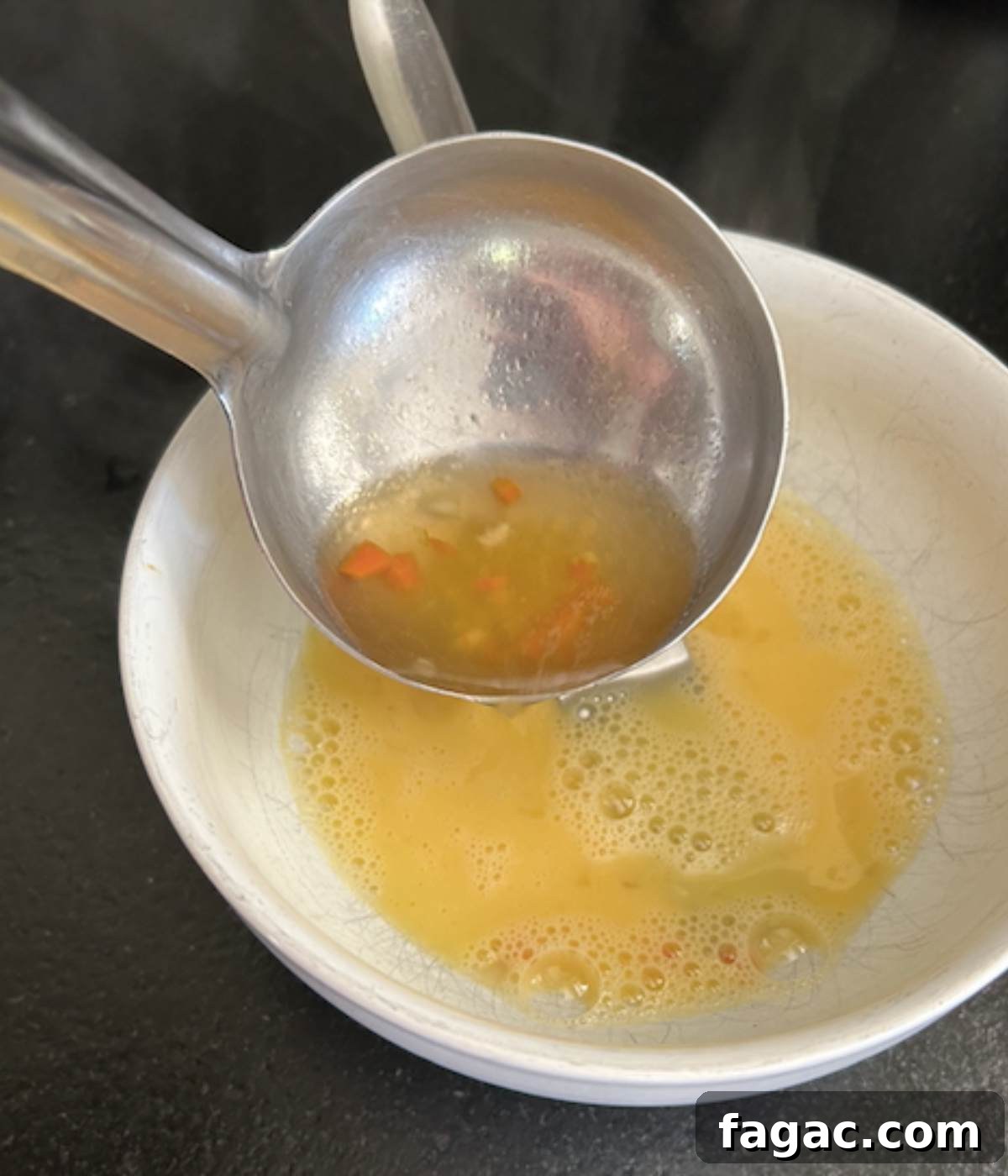 Ladle pouring broth into egg to cook it.