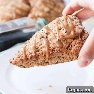 Flaky Banana Scones Without Eggs: Simple Recipe for Tea Time 2 Hand holding a Banana Black Sesame Vegan Scones with Maple Tahini Glaze.
