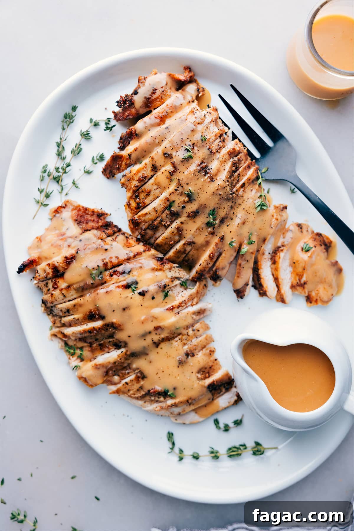Crockpot Cooked Turkey Breast Served with Gravy and Fresh Herbs Sliced turkey breast cooked in a crockpot, served on a plate topped with gravy and garnished with fresh herbs.