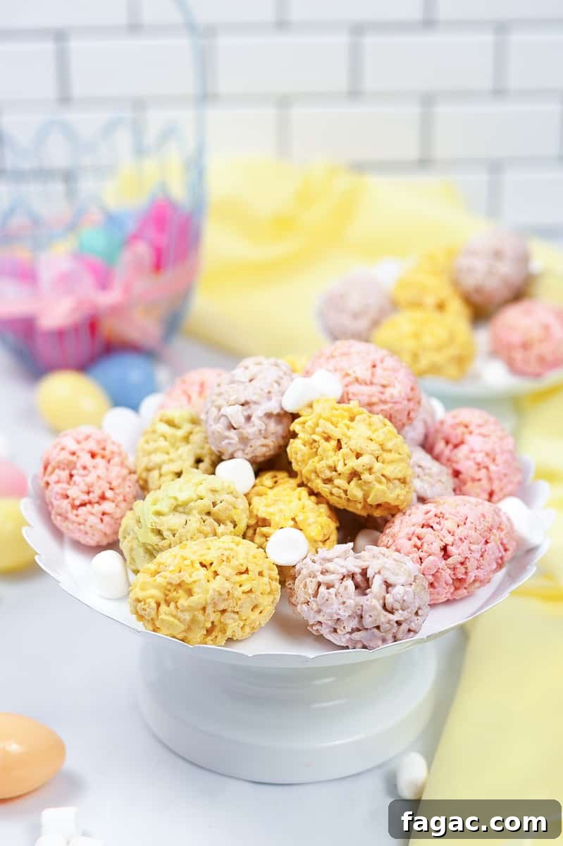 Easter Rice Krispie Treats: Festive Bunny and Egg Recipes 2 pink, purple, and yellow easter rice krispie treats on a white serving platter with plastic Easter eggs in the background