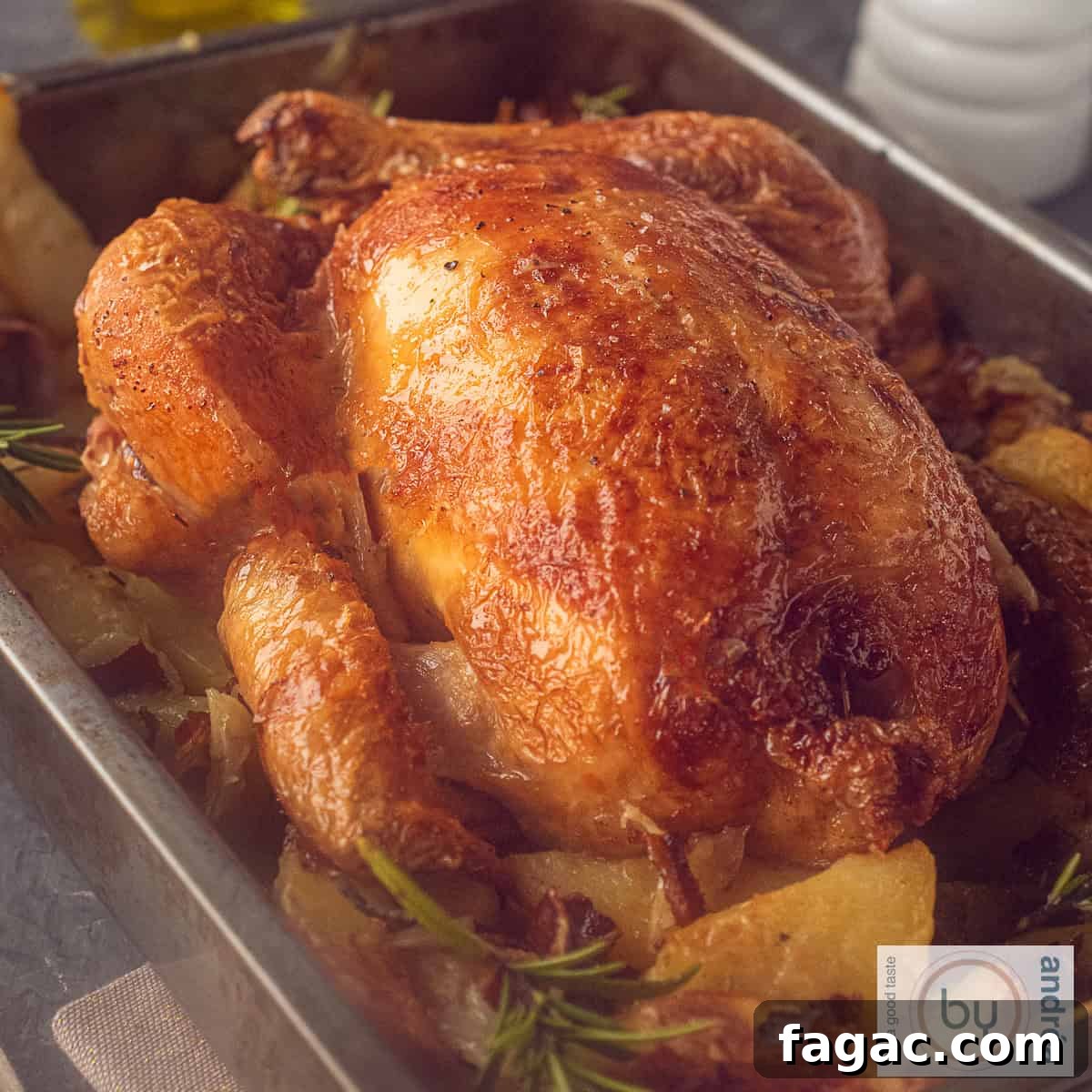 Crispy Roast Chicken with Herbed Potatoes Recipe 3 A square picture of a roasting pan filled with roasted chicken and potatoes, bacon and rosemary