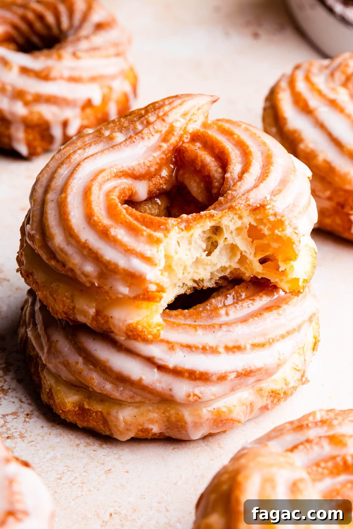 Classic French Cruller Donuts: Light, Crispy Pastry Recipe 2 side super close up at glazed cruller doughnut with bite missing on top of another doughnut