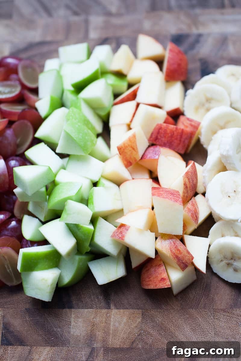 Festive Creamy Fruit Salad Recipe for Christmas Parties 3 Wooden cutting board with chopped fruit.