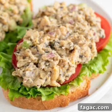 Vegan Tuna Recipe: Plant-Based Tuna Alternative Guide 9 Vegan tuna on a slice of bread, with lettuce and tomato slices, on a white plate.
