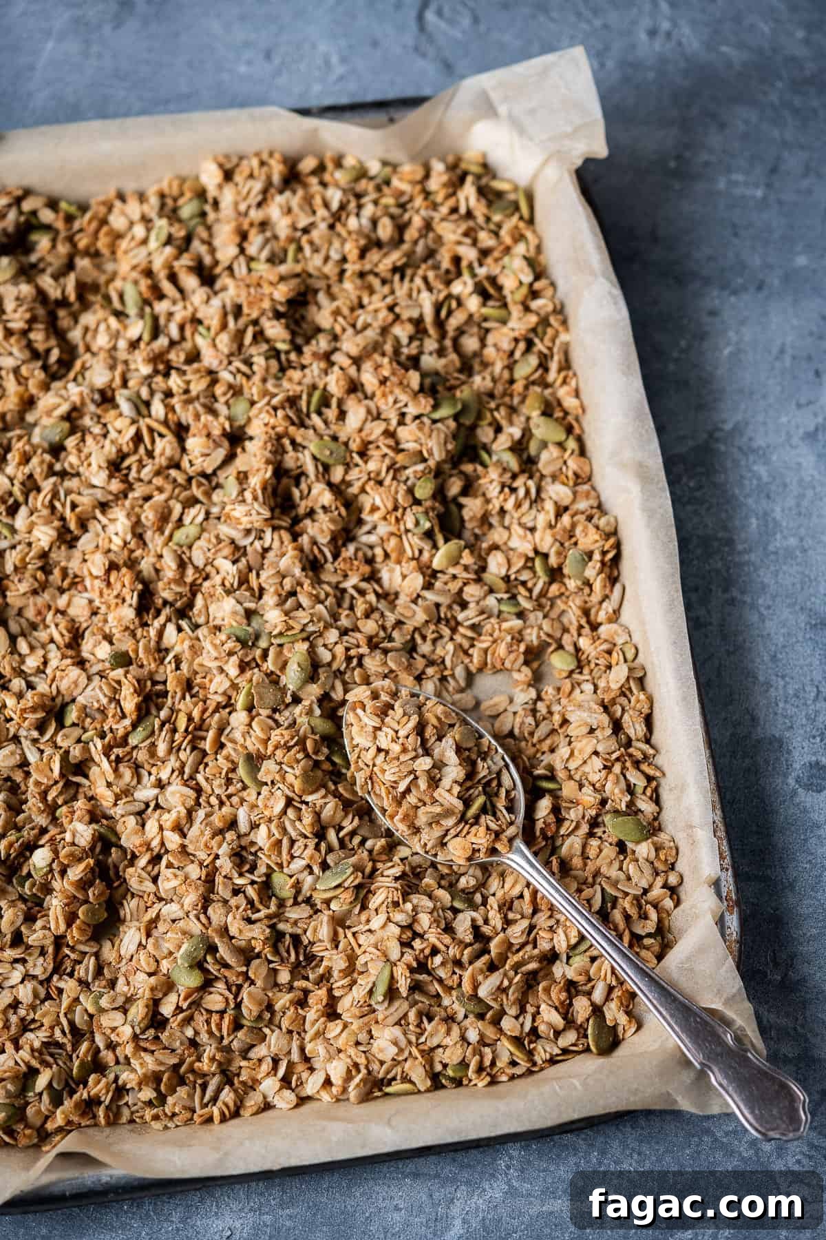 Vegan granola - customizable and easy to make a tray of basic vegan granola on a grey background.
