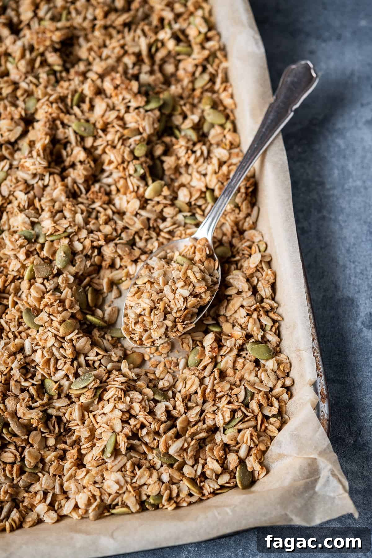 Spoonful of granola Vegan granola on a baking tray with a metal spoon.