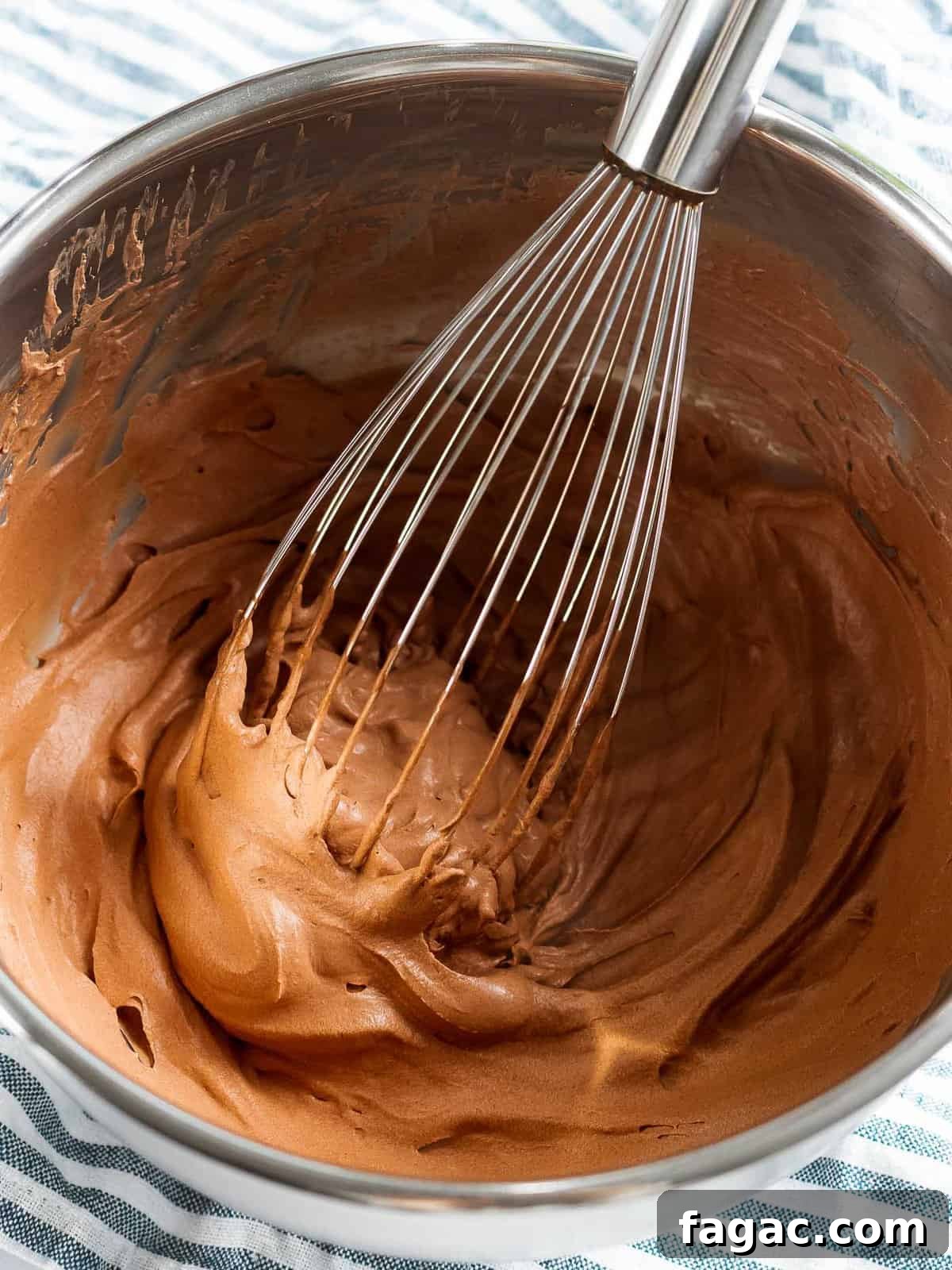 Chocolate whipped cream in a bowl with a whisk.