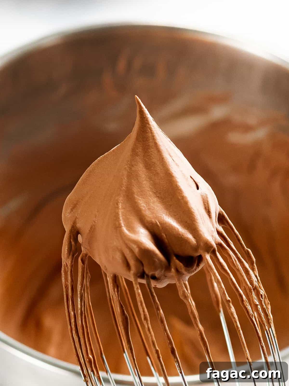 Fluffy homemade chocolate whipped cream on the end of a whisk.