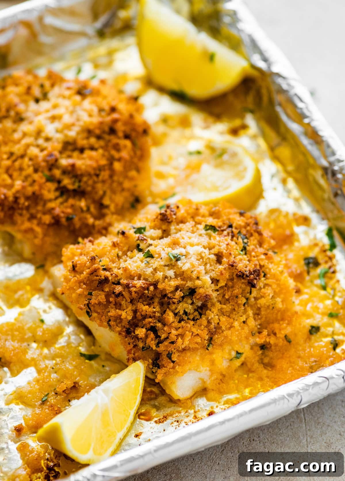 Crispy Panko-Baked Cod with Lemon Garlic Sauce 2 baked cod with panko after baking on the baking sheet. Lemons on the tray.