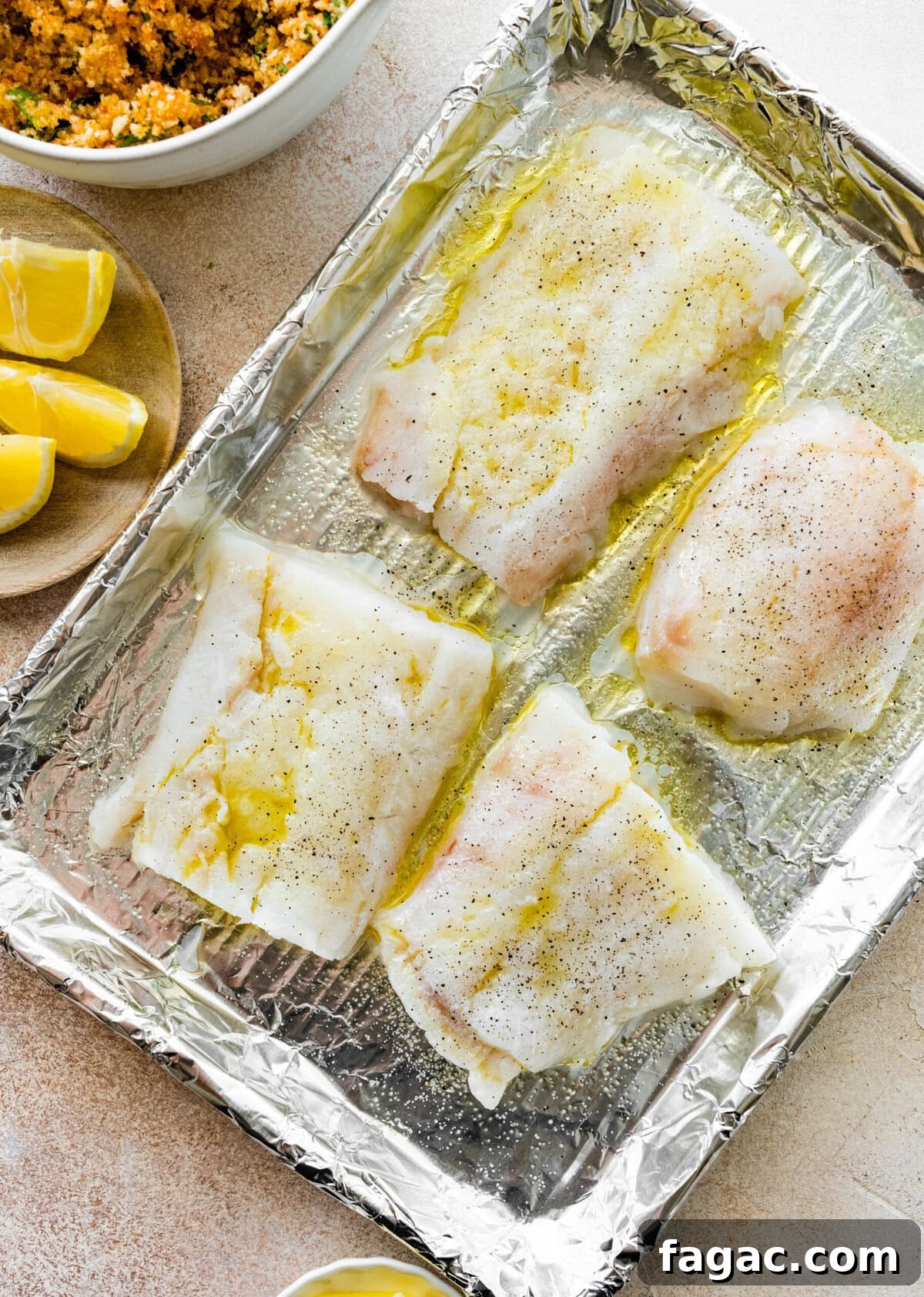 Crispy Panko-Baked Cod with Lemon Garlic Sauce 8 cod on a baking sheet with tin foil on it. Olive oil on the cod.