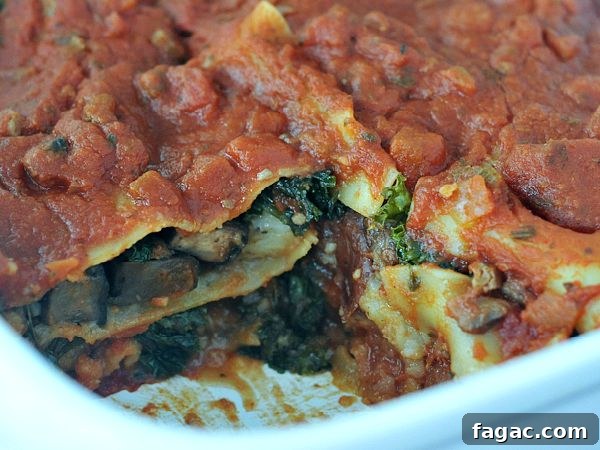 Hearty Portobello Kale Lasagna @spabettie #vegan #oilfree #glutenfree #comfortfood Hearty portobello kale lasagna with red sauce in a white baking dish.