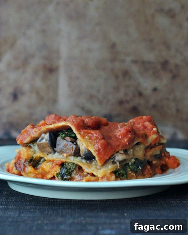 Hearty Portobello Kale Lasagna @spabettie #vegan #oilfree #glutenfree #comfortfood Hearty portobello kale lasagna with red sauce on a white plate.