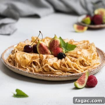 Folded French crepes topped with fresh fruit on a grey plate.