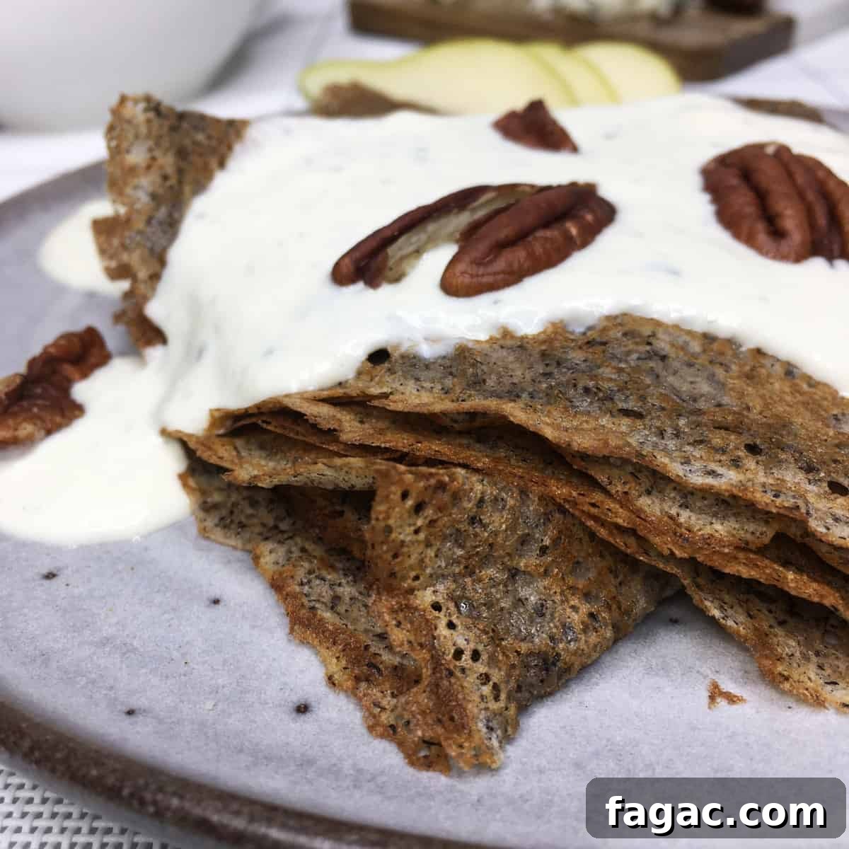 Folded French galettes with a savory filling, pecans, and slices of pear on a grey plate.
