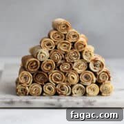 Rolled nalesniki arranged in a pyramid on a marble board.