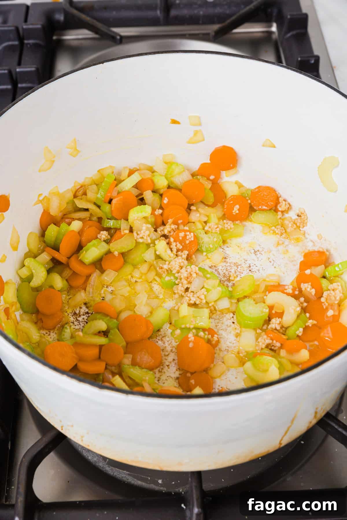 Comforting Gluten-Free Chicken Noodle Soup Recipe 5 A white dutch over of diced celery, carrots, onion and minced garlic sautéed in olive oil.