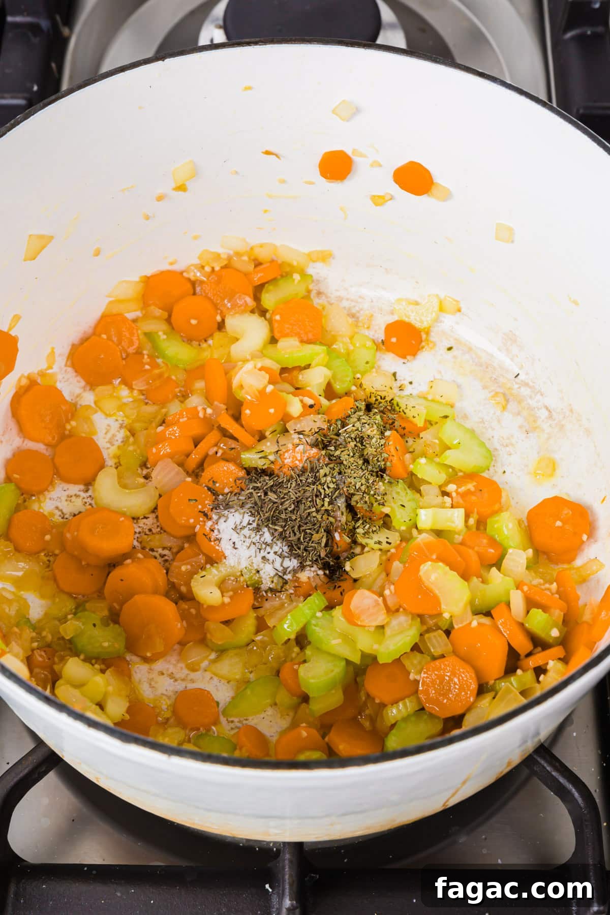 Comforting Gluten-Free Chicken Noodle Soup Recipe 6 A white dutch oven with sliced carrots, celery, diced onion, salt, dried herbs and minced garlic cooked in olive oil.