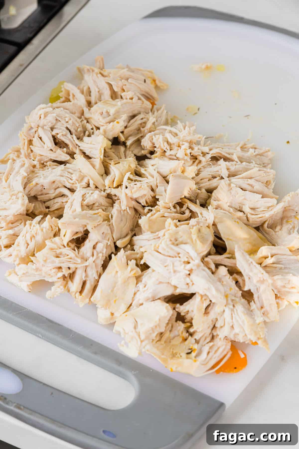 Comforting Gluten-Free Chicken Noodle Soup Recipe 10 A cutting board with shredded chicken breast on it.