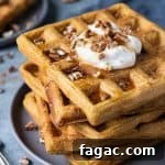 Fluffy Vegan Pumpkin Waffles with Cinnamon Maple Syrup 4 A stack of vegan pumpkin waffles on a grey plate.