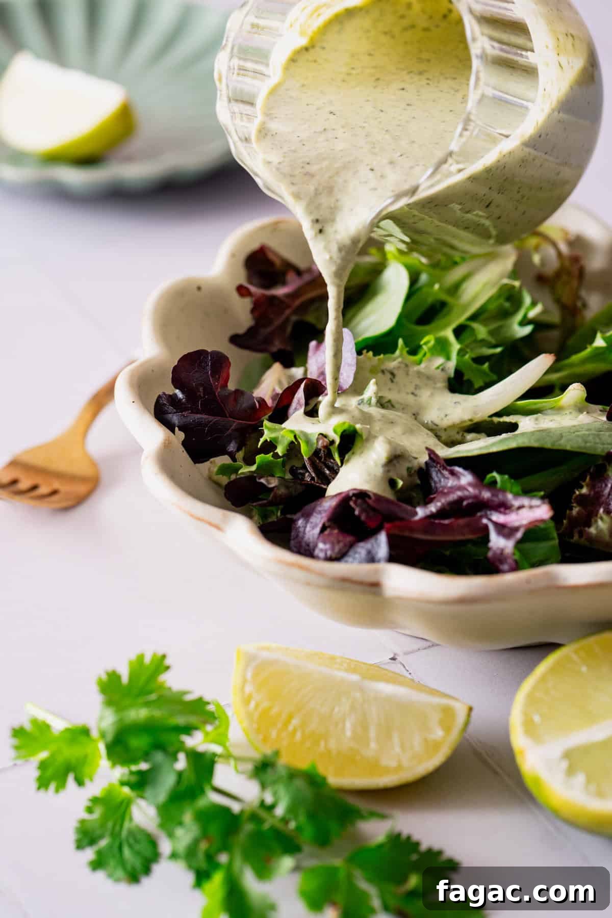 Vegan Cilantro Lime Dressing — Dairy-Free Paleo Recipe 2 A creamy dressing being poured onto a salad.