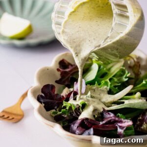 Vegan Cilantro Lime Dressing — Dairy-Free Paleo Recipe 12 A creamy cilantro lime dressing being poured onto a salad.