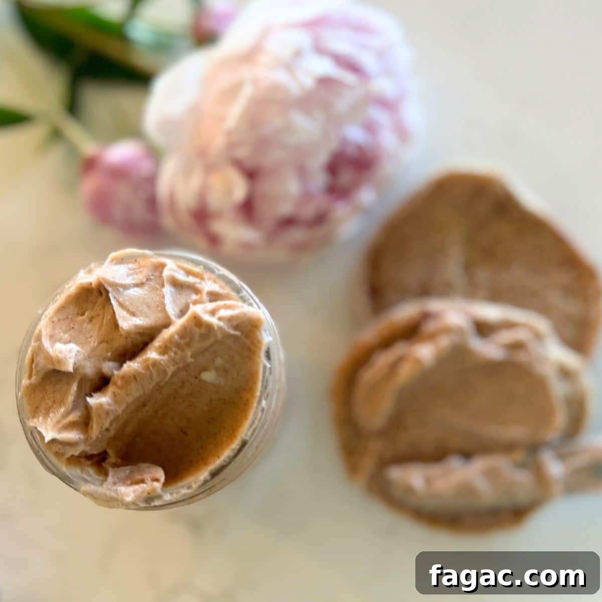 Texas roadhouse cinnamon honey butter in small mason jar and spread on a roll with a Peony on the counter top