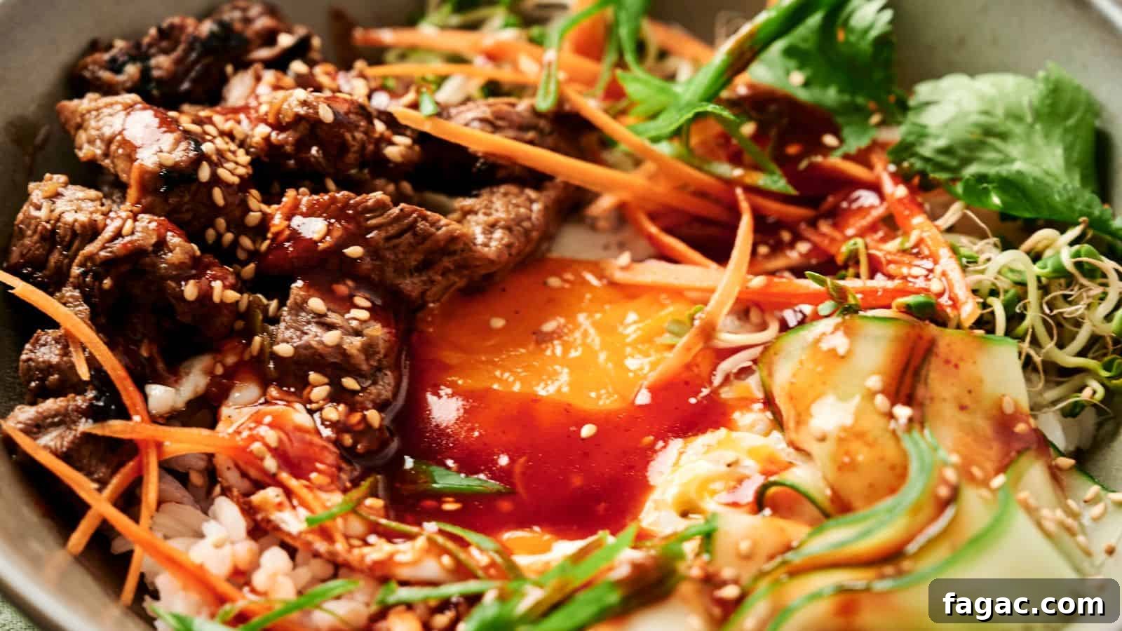 A bowl of bibimbap with sliced beef, egg yolk, carrots, cucumber, greens, and bean sprouts, topped with sesame seeds and red sauce.