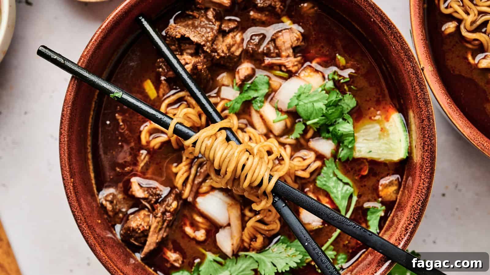 A bowl of ramen with meat, cilantro, and a lime wedge, topped with noodles wrapped around chopsticks.