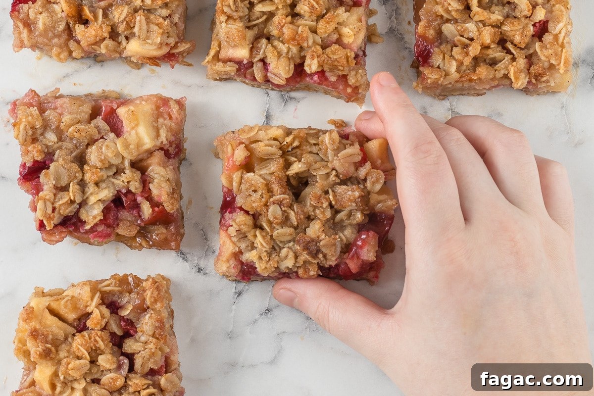 Apple Plum Crumble Bars with Oat Topping Recipe 3 A hand grabbing the Apple and Plum Crumble Bars