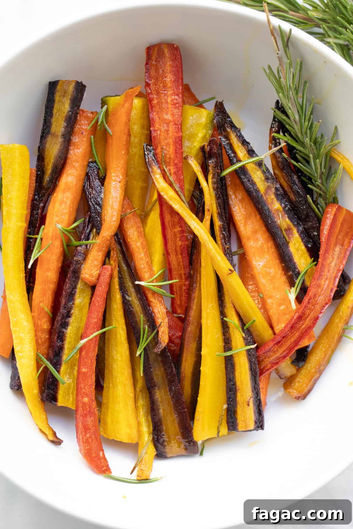 Rosemary Roasted Carrots with 4 Simple Ingredients 2 close up of rosemary roasted carrots in a white serving dish.