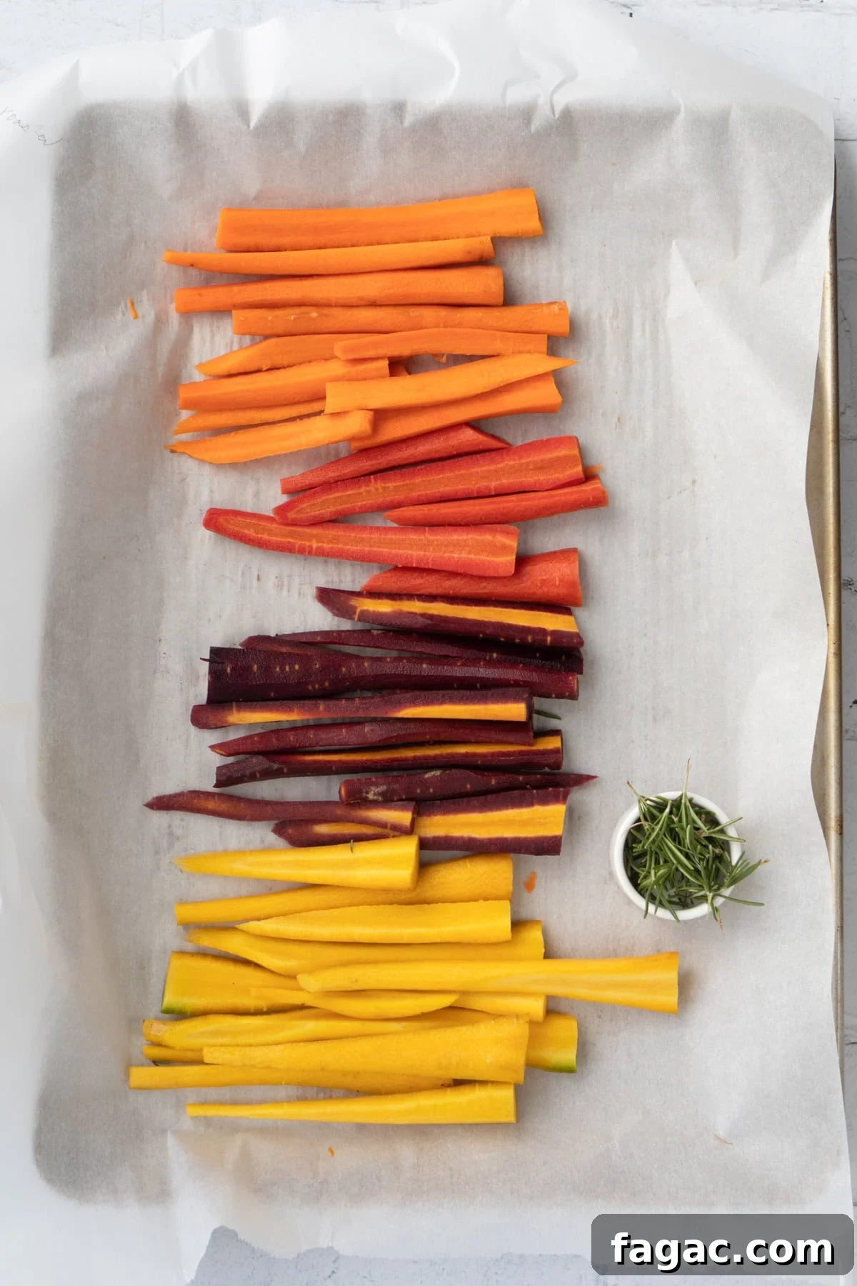 Rosemary Roasted Carrots with 4 Simple Ingredients 4 cut rainbow carrots on a parchment line baking sheet.