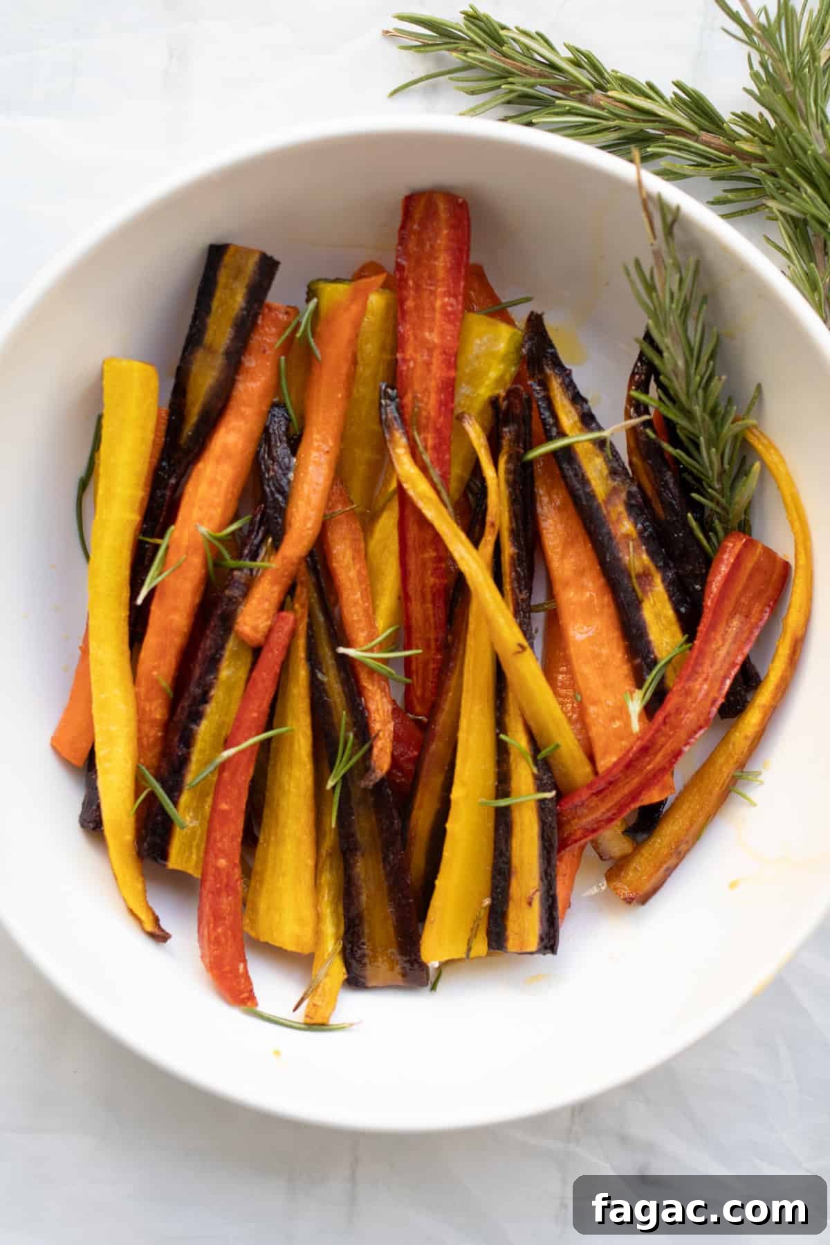 Rosemary Roasted Carrots with 4 Simple Ingredients 6 rainbow rosemary roasted carrots in a white serving dish.