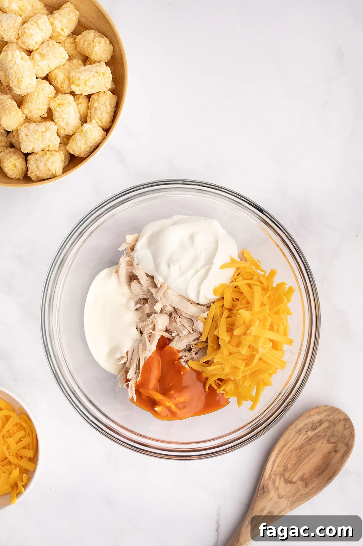 Buffalo Chicken Tater Tot Casserole Recipe with Cheesy Buffalo Sauce 4 Chicken, sour cream, buffalo sauce, and cheese in a mixing bowl.