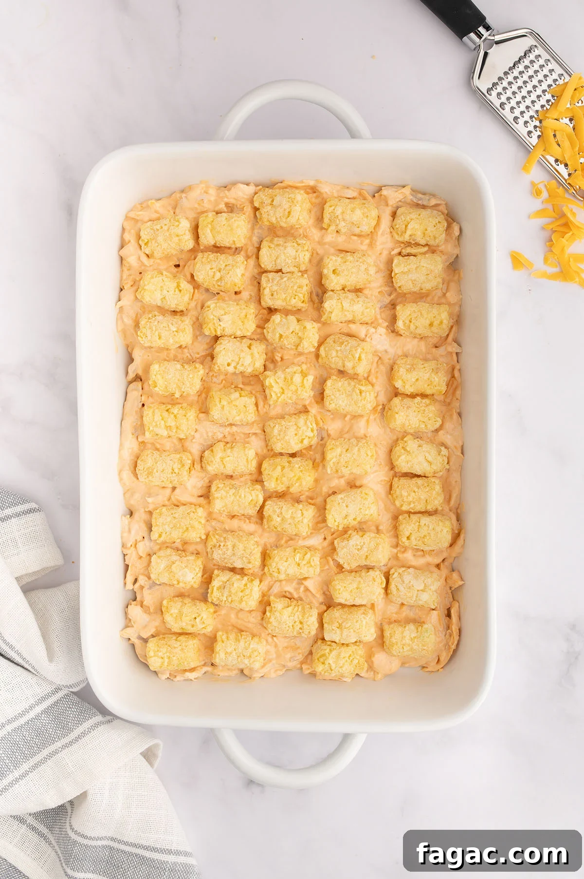 Buffalo Chicken Tater Tot Casserole Recipe with Cheesy Buffalo Sauce 7 Tater tots placed over the buffalo chicken filling in the baking dish.