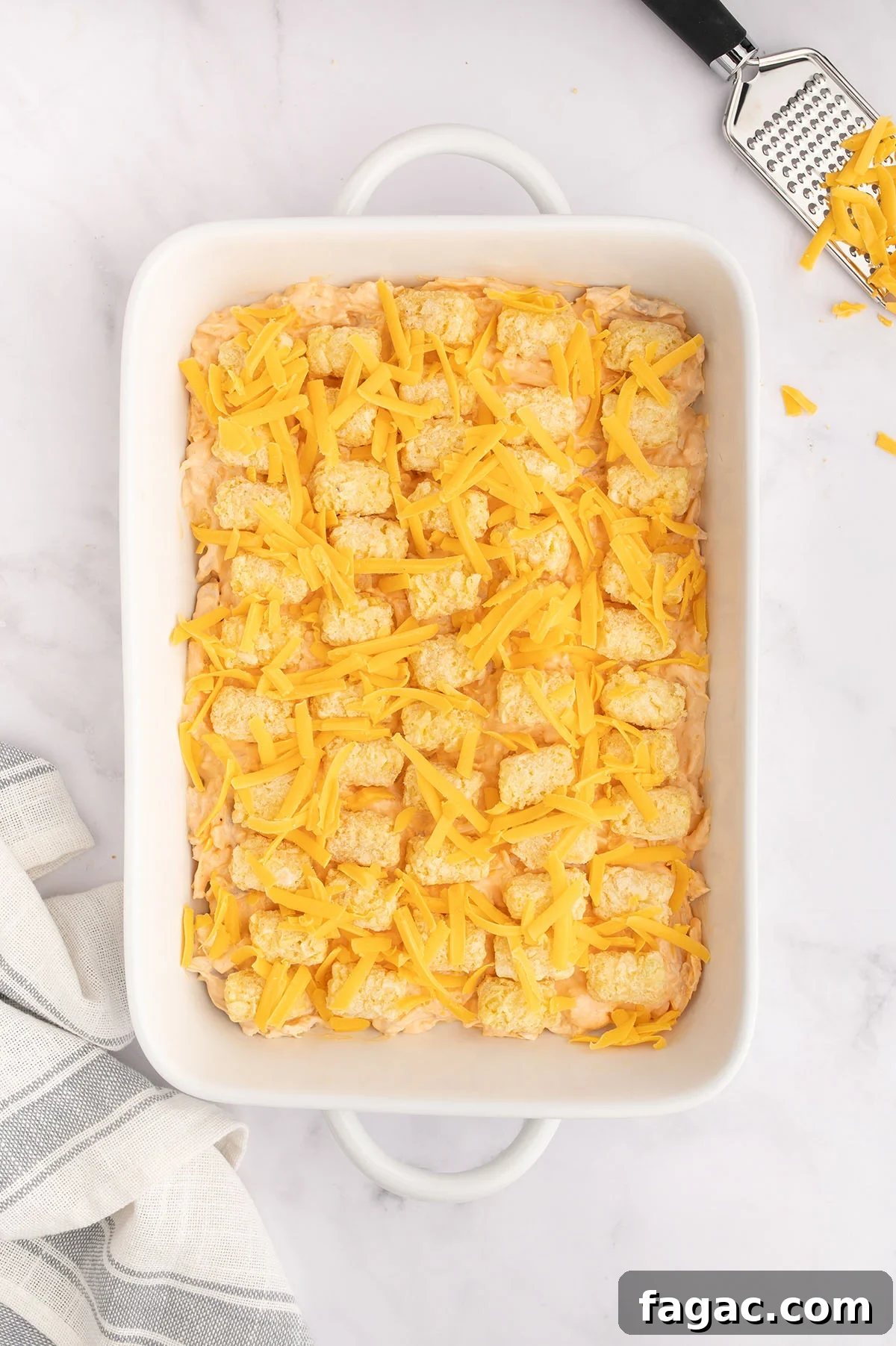 Buffalo Chicken Tater Tot Casserole Recipe with Cheesy Buffalo Sauce 8 Cheese is added over the top of the tater tots and buffalo chicken filling in the baking dish.