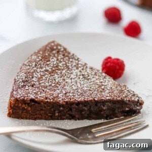 Authentic Swedish Kladdkaka: Gooey Sticky Chocolate Cake Recipe 11 Closeup of a slice of kladdkaka on a plate next to a fork and raspberries.